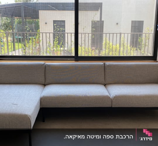 ספה אפורה ליד חלון גדול עם נוף לגינה